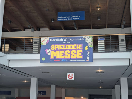 Zu sehen ist das Wilkommensbanner der SpielDoch! Messe. Der markante gelbe Schriftzug auf blauen Grund hat einen hohen Wiedererkennungswert.