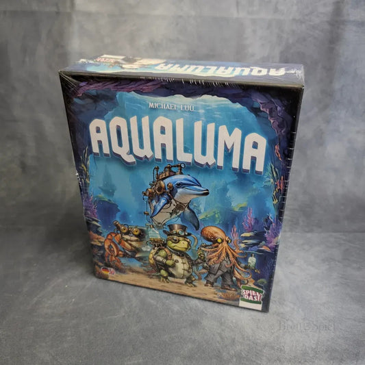 Eine Schachtel von Spiel Das! Aqualuma, ein kooperatives Brettspiel mit Unterwasserkreaturen - Delfin mit Taucher, Krabben, Schildkröten in Tauchausrüstung - vor einer farbenfrohen Kulisse für spannende Unterwasserabenteuer.