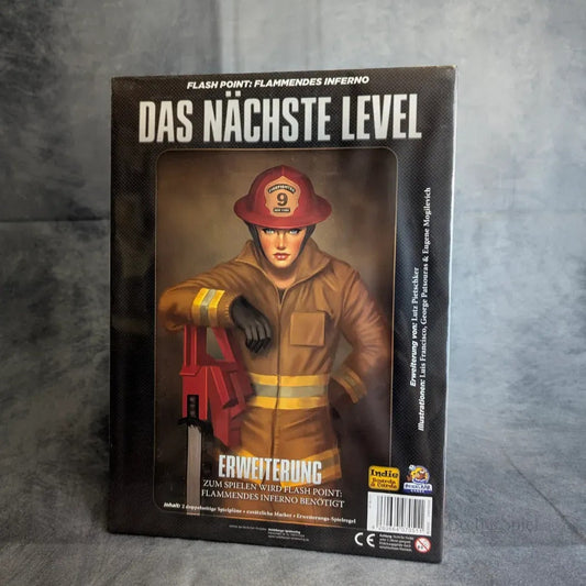 Das Bild zeigt die Schachtel für Flash Point: Die nächste Level Erweiterung von Heidelbär Games, die einen Feuerwehrmann in Uniform und Helm zeigt, der eine Axt vor einer verrauchten Kulisse hält.