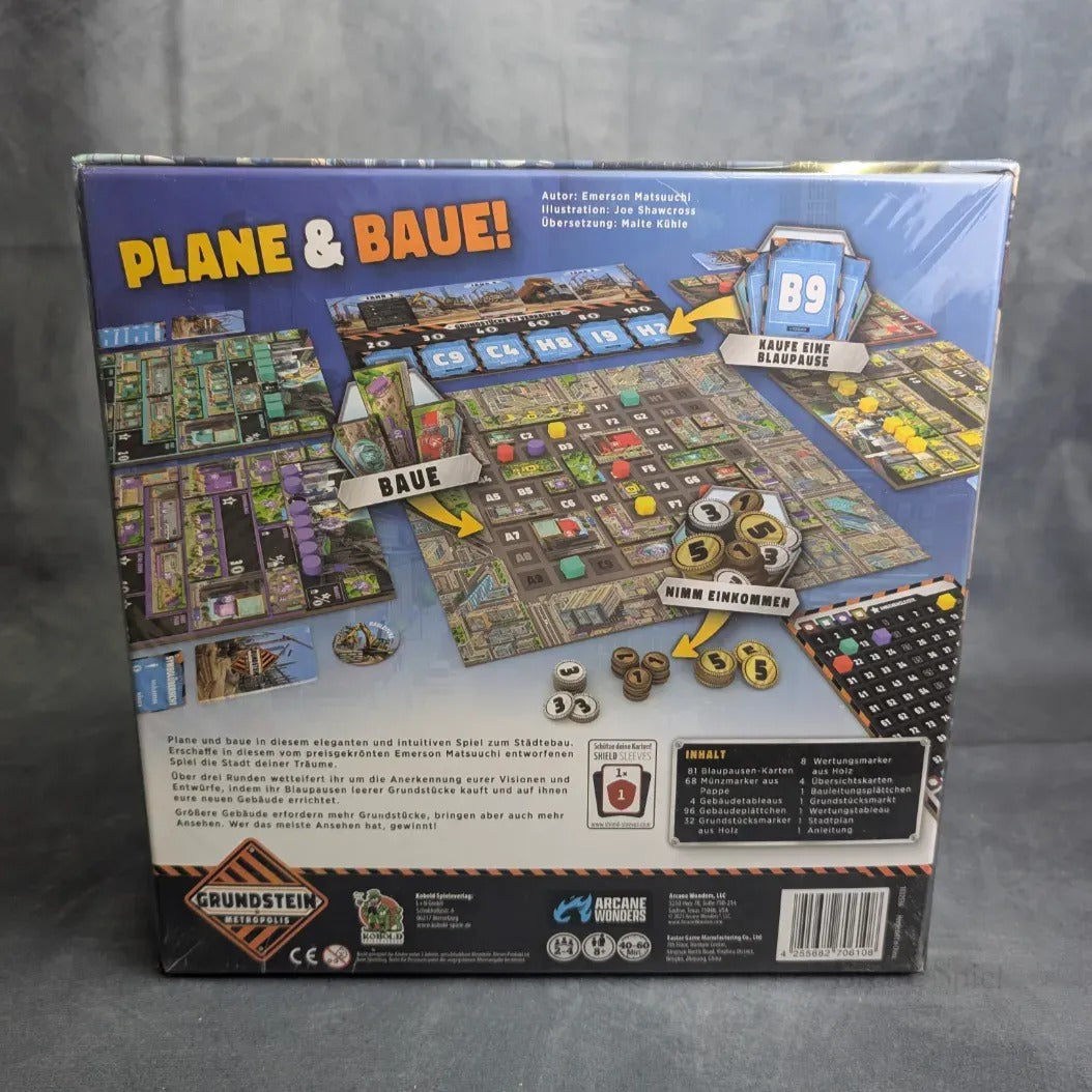 Rückseite einer Grundstein von Metropolis-Schachtel von Kobold Spiele, die ein lebendiges Spielbrett, Polyomino-Steine, Spielsteine und Karten zeigt. Der deutsche Text und die Diagramme erklären den Aufbau und die Regeln für dieses strategische Städtebauspiel.