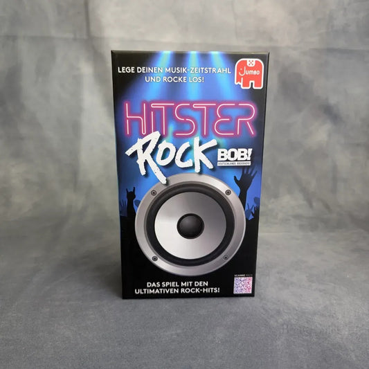 Eine Schachtel von Hitster: Rock von Pegasus Spiele steht auf einer grauen Fläche und zeigt einen großen Lautsprecher, einen Text im Neon-Stil und jubelnde Fan-Silhouetten. Der deutsche Text und das Pegasus Spiele-Logo feiern diese Hommage an die Rockmusik.