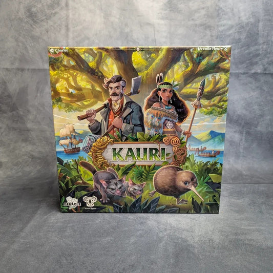 Das Brettspiel „Kauri“ von Koalla Spiele zeigt einen Mann mit einer Axt und eine Frau in traditioneller Kleidung unter einem großen Baum, mit einheimischen Tieren und Segelschiffen – ein asymmetrisches Strategiespiel, das in Neuseeland spielt.