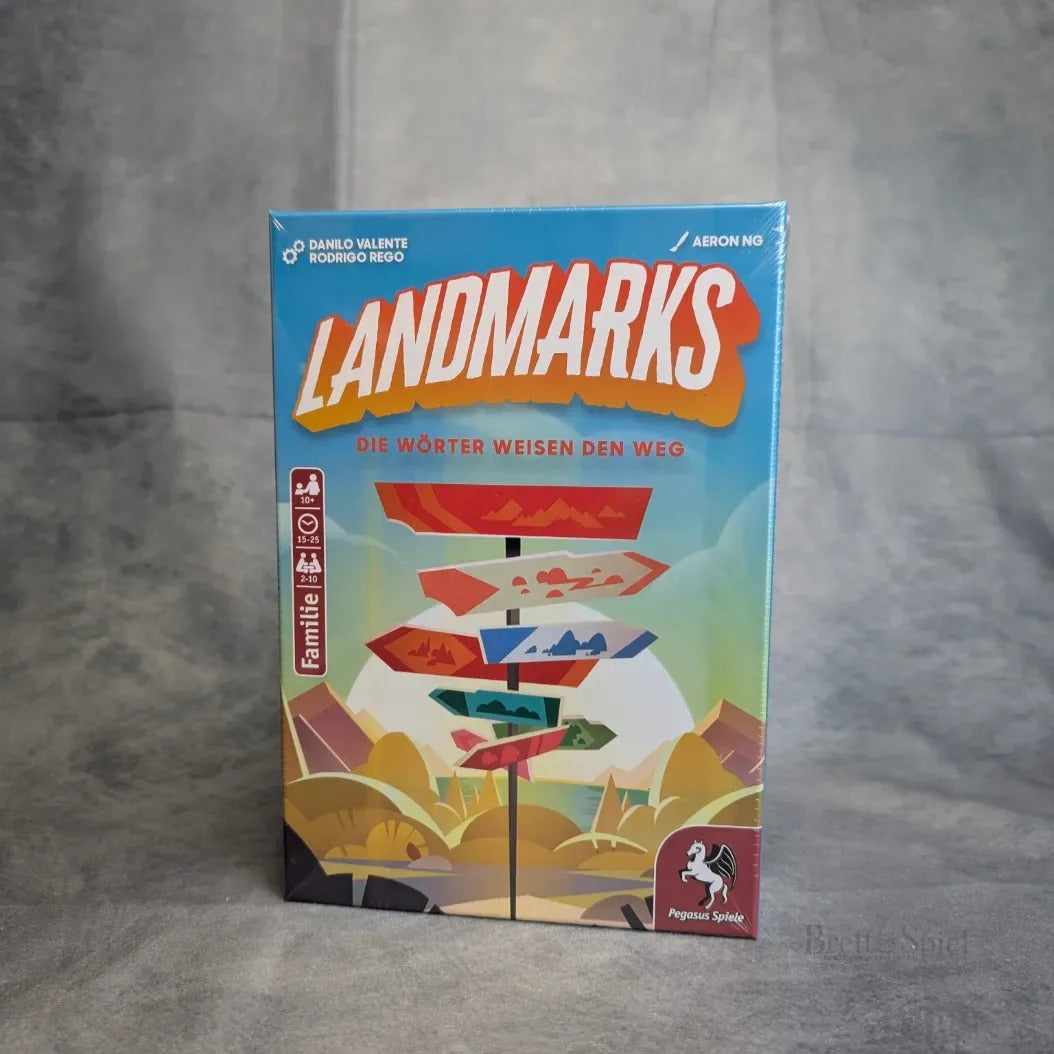 Eine Schachtel des Brettspiels „Landmarks“ von Pegasus Spiele mit bunt illustrierten Wegweisern und Bergen auf dem deutschen Cover und dem Logo unten rechts – ideal für Ihr Expeditionsteam auf der Suche nach Juwelen.