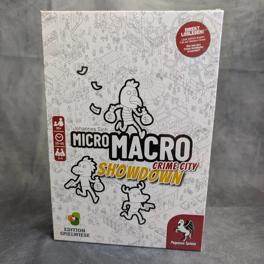 Das Bild zeigt die Verpackung von Pegasus Spiele's MicroMacro: Crime City das ultimative Bundle, mit Cartoon-Figuren, die über einen Stadtplan laufen. Auf dem Cover sind Logos und Altersempfehlungen abgebildet.