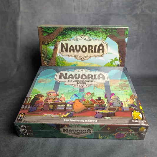 Zwei farbenfrohe Brettspielschachteln von Strohmann Games werden gezeigt - eine hochkant und eine flach - beide mit dem Titel "Navoria & Die vergessenen Lande", die mit ihrer lebhaften Fantasiekunst ein spannendes Worker-Placement-Abenteuer andeuten.