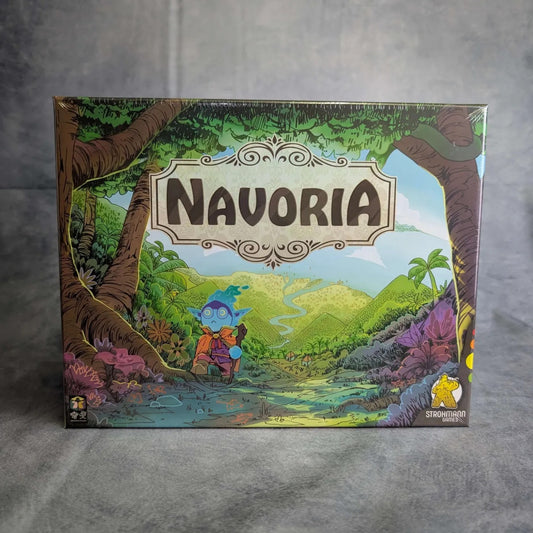 Die farbenfrohe Schachtel von Navoria & Die vergessenen Lande von Strohmann Games zeigt ein blaues Fantasiewesen mit Brille auf einem üppigen Waldpfad und verspricht ein spannendes Worker-Placement-Abenteuer unter einem strahlenden Himmel.