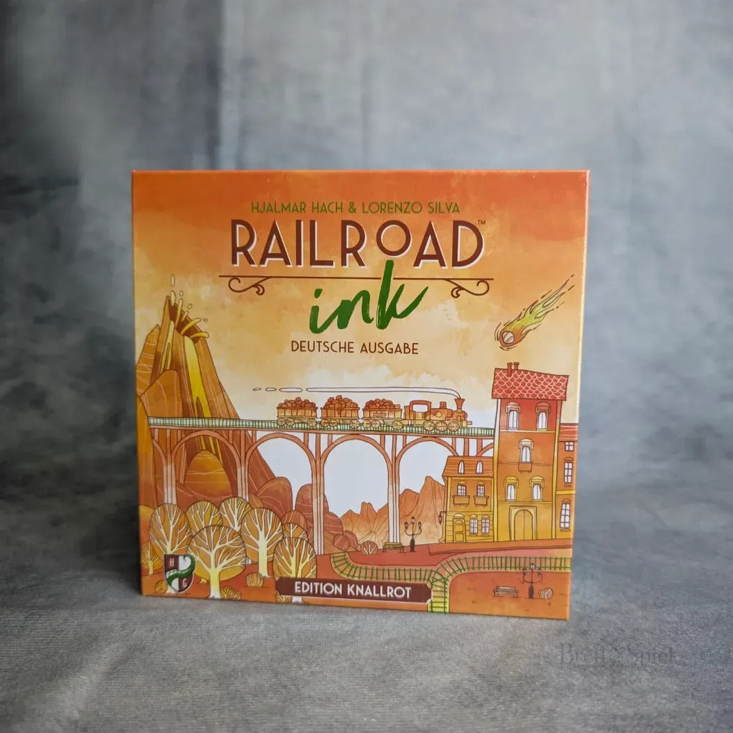 Die Abbildung zeigt die Schachtel für Railroad Ink: Edition Knallrot von Heidelbär Spiele. Das gelb-orangefarbene Cover zeigt Züge, Schienen, Gebäude, Bäume, einen Meteor und einen deutschen Text, der die Herausforderungen des Verkehrsnetzes hervorhebt.