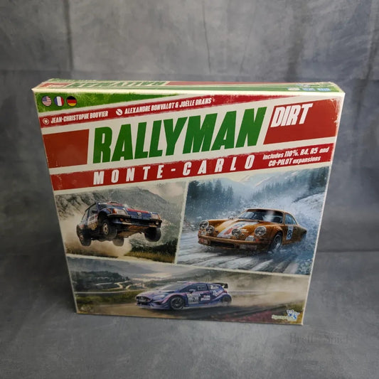Box für Rallyman: DIRT - Monte-Carlo von JoeKas World GmbH zeigt Rallye-Autos, die auf unbefestigten Straßen mit verschneiten Bergen im Hintergrund fahren. Die Rallye Erweiterung Box ist eingeschweißt und mit roten und grünen Aufklebern versehen.