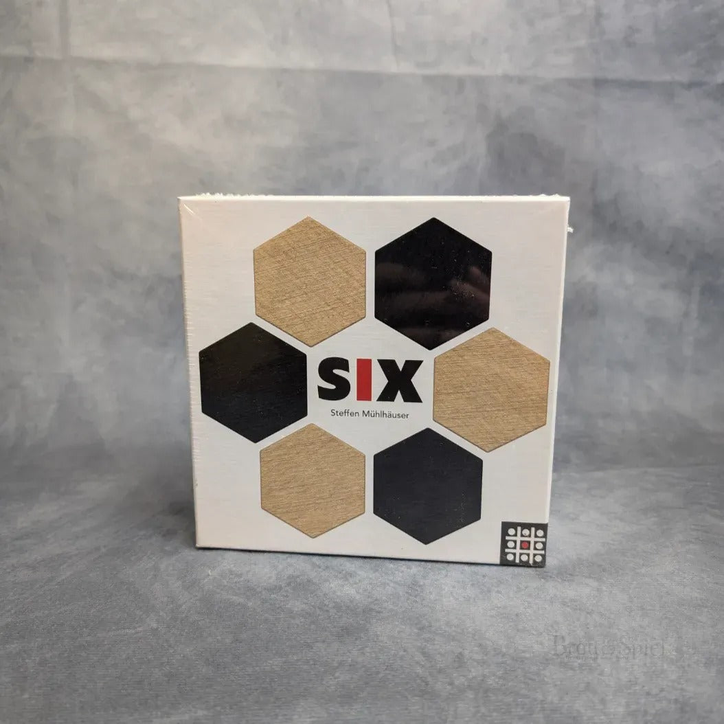 Eine quadratische Spielschachtel mit dem Titel Six von Steffen Spiele zeigt sechs Sechsecke - drei schwarze, drei mit Holzstruktur - in zwei Reihen auf weißem Grund. Dieses strategische Brettspiel fordert Sie heraus, das sechseckige Plättchen-Legepuzzle zu meistern.