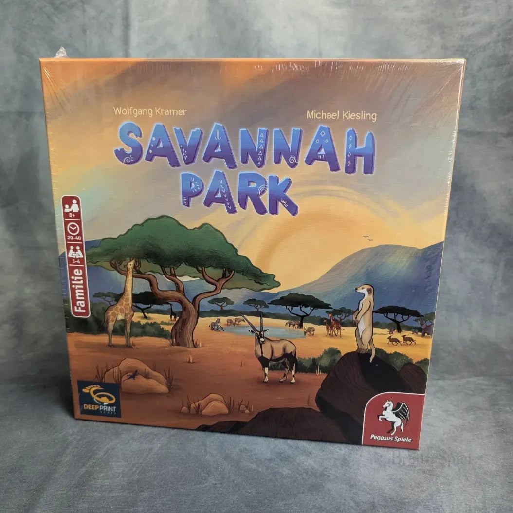 Eine versiegelte Schachtel Savannah Park von Pegasus Spiele, ein interaktives Puzzle-Brettspiel mit illustrierten Savannentieren wie Giraffen und Erdmännchen, sowie Akazienbäumen und Bergen unter einem Sonnenuntergangshimmel.