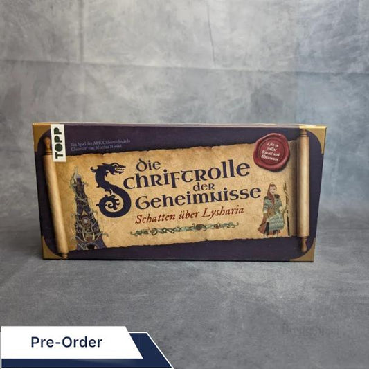 Die rechteckige Box „Die Schriftrolle der Geheimnisse – Schatten über Lysharia“ vom Frech Verlag präsentiert mittelalterliche Kunstwerke, eine Schriftrolle, einen Zauberer und einen Ritter – ideal für Abenteuer und Rätsel – auf einem schlichten grauen Hintergrund.