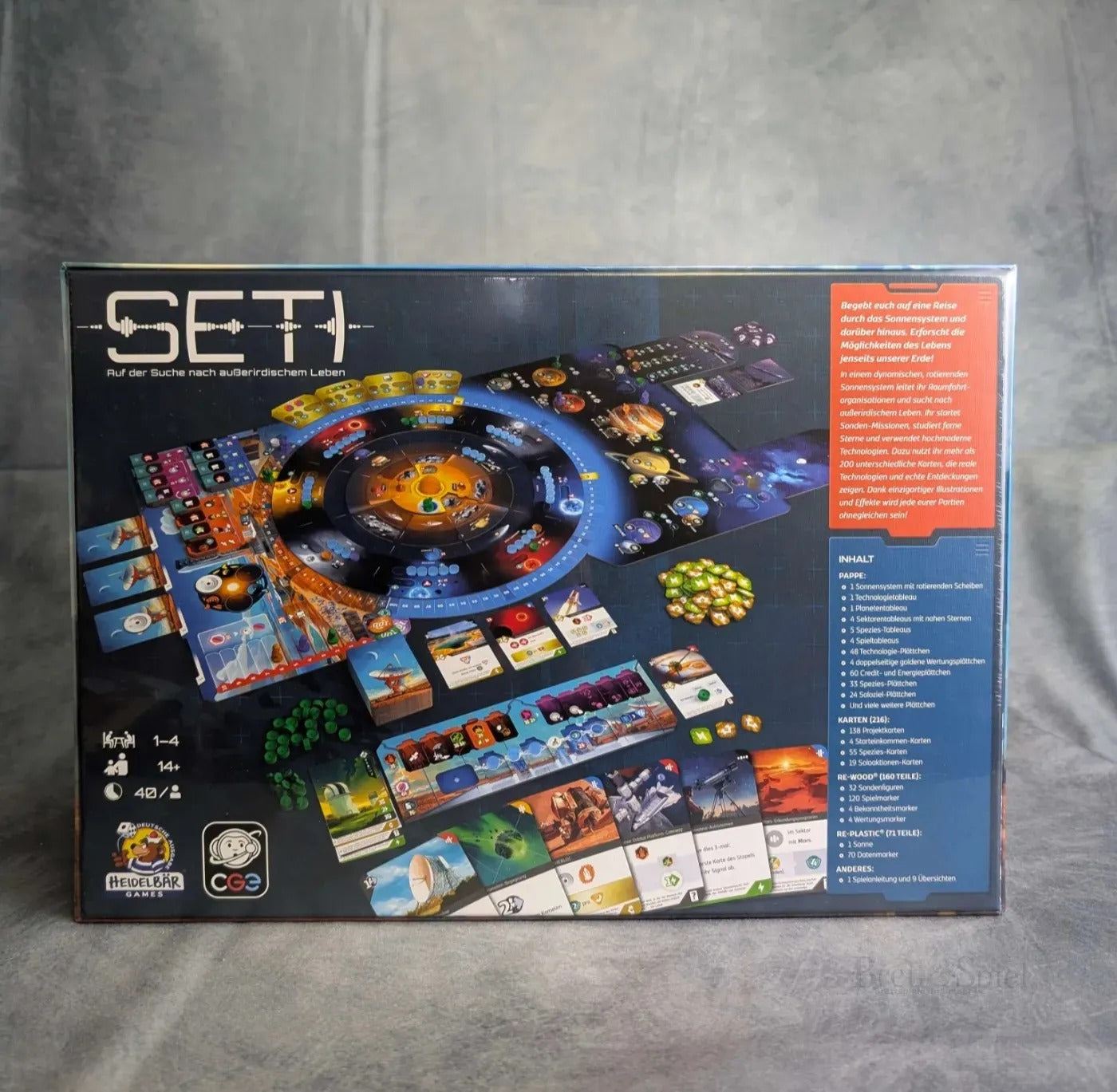 Auf der Rückseite der Schachtel SETI: Auf der Suche nach außerirdischem Leben von HeidelBÄR Spiele befinden sich illustrierte Karten, Spielsteine, Spielbretter und ein kreisförmiges Spielbrett, sowie Regeln und Features, die die Spieler zur Suche nach Exoplaneten und außerirdischem Leben einladen.