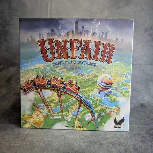 Die Box Unfair - Fiese Freizeitparks von Corax Games zeigt einen markanten Titel über lebendigen Freizeitpark-Szenen - Achterbahn, Reiter, Heißluftballon, Attraktionen, Grünanlagen und Stadtsilhouette - und enthält die Erweiterungen "ABJW" und "CHKO".