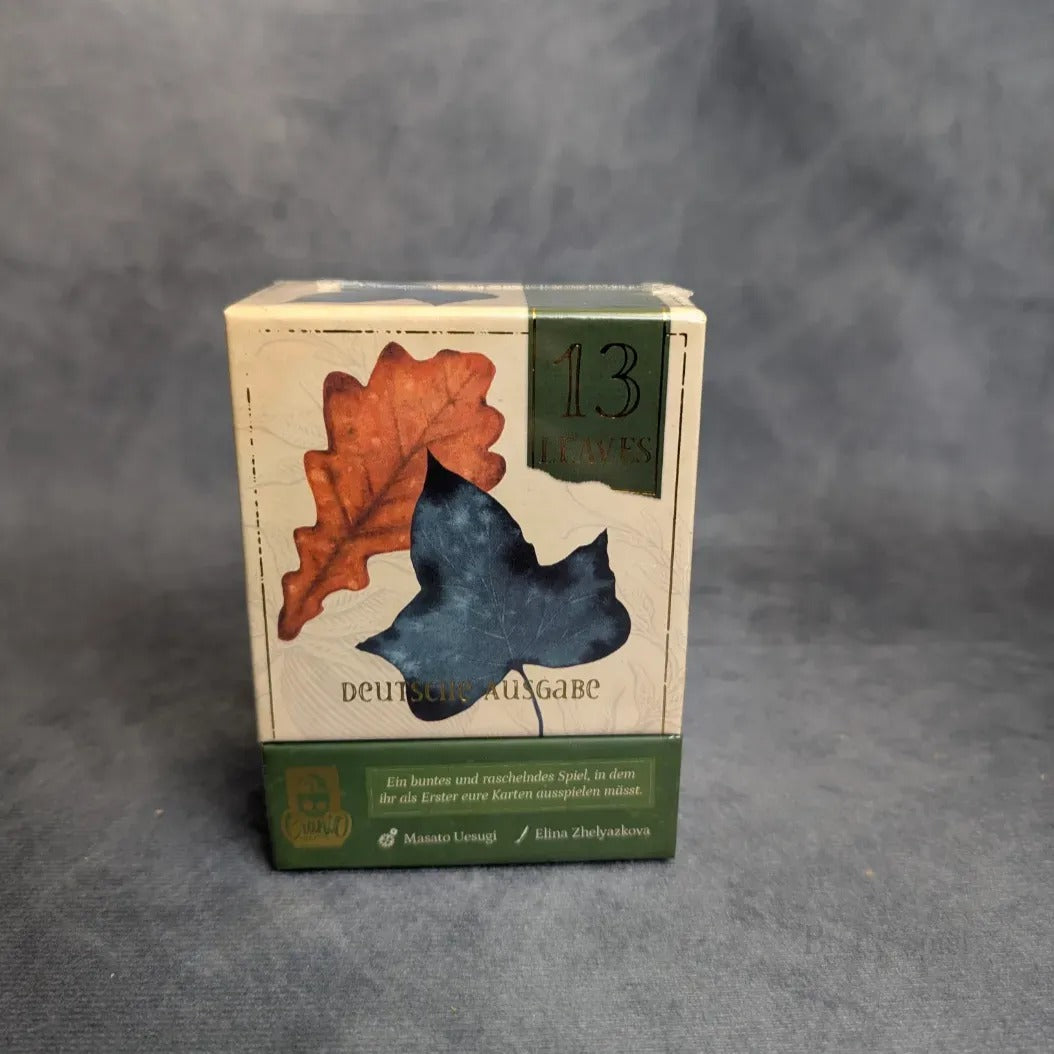13 Leaves von JoeKas World GmbH ist ein Taktikspiel mit rotbraunen und dunkelblauen Blättern auf der Vorderseite und deutschem Text darunter auf neutralem Hintergrund.