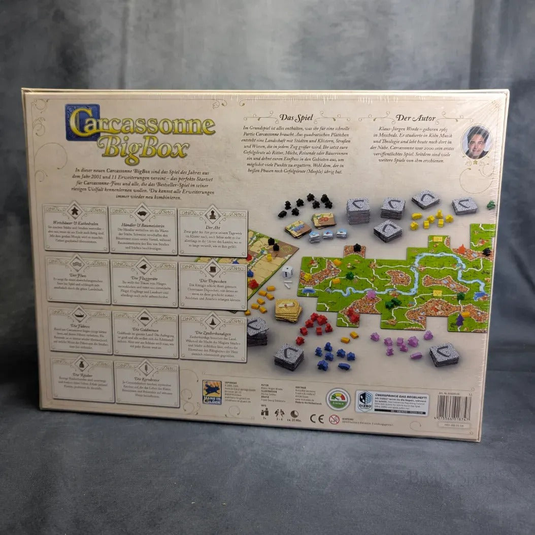 Die Rückseite der Carcassonne Big Box 3.1 von Hans im Glück zeigt den Titel des Spiels, die Beschreibung, die enthaltenen Erweiterungen, ein Foto des Aufbaus mit Plättchen und Figuren sowie Symbole für Spielerzahl und Altersempfehlung.