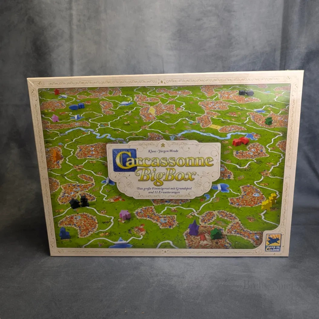 Das Bild zeigt die Hans im Glück Carcassonne Big Box 3.1 mit einem detaillierten Spielplan mit Feldern, Straßen und Städten, lebendigen Spielsteinen und den Highlights der vielen Erweiterungen, die in diesem umfangreichen Set enthalten sind.