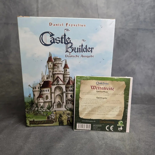Eine verpackte deutsche Ausgabe von Brett&Spiels Castle Builder + Wettstreit Erweiterung steht aufrecht, mit einem Regelblatt mit Baronen und Goldmünzen, vor einem grauen, strukturierten Hintergrund.