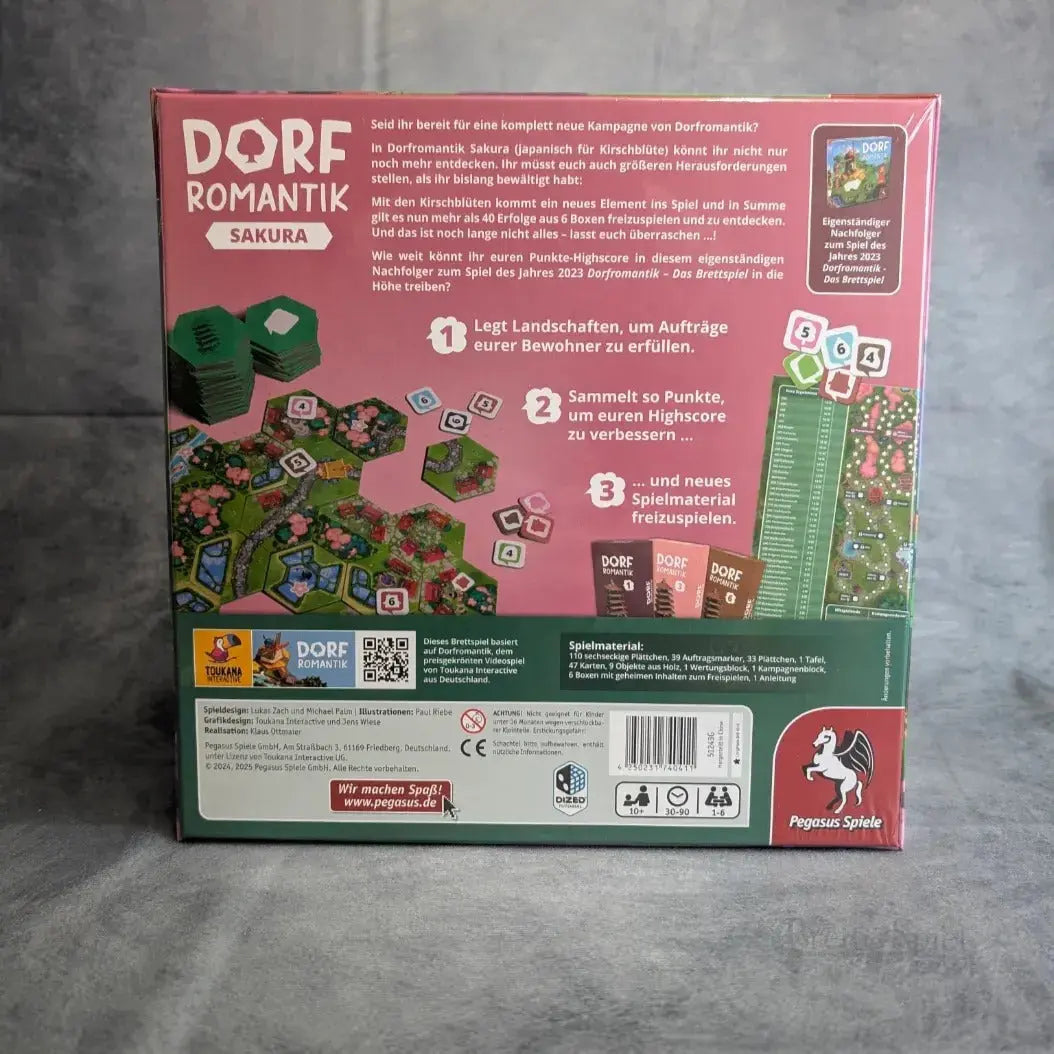 Auf der Rückseite einer Dorfromantik: Sakura-Box von Pegasus Spiele sind Sechseckplättchen, Anzeigetafeln, Spielsteine und ein deutscher Text abgebildet, der das Landschaftsdesign-Thema hervorhebt und detaillierte Spielanweisungen liefert.