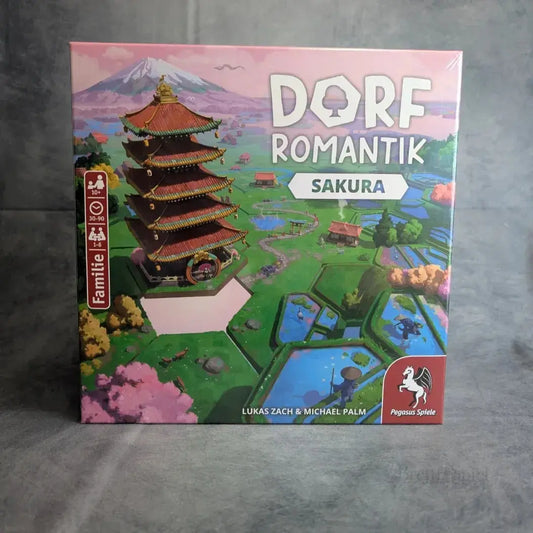 Dorfromantik: Sakura, ein Brettspiel von Pegasus Spiele, besticht durch lebendige Illustrationen mit einer Pagode, Kirschblüten, Teichen, grünen Feldern und Bergen. Das Pegasus Spiele-Logo ist unten rechts abgebildet.
