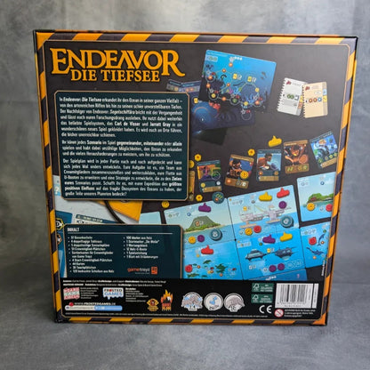 Die Rückseite der Endeavor: Die Tiefsee Box von Frosted Games zeigt lebendige Komponenten, Karten und Spielbretter mit deutschen Beschreibungen, Symbolen und einem Kennerspiel des Jahres 2025 Logo am unteren Rand.