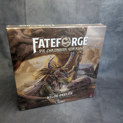 Eine Schachtel Fateforge: Wilde Seelen Erweiterung von Squink GmbH zeigt Fantasy-Kunst eines gehörnten Wesens mit einem Stab in einer mystischen Landschaft. Die Box, möglicherweise mit Miniaturen, ruht auf einer grauen Oberfläche vor einem dunklen Hintergrund.