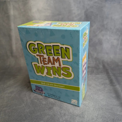 Eine versiegelte Schachtel der Green Teams Win des PD Verlags steht aufrecht auf einer grauen Fläche, mit buntem Schriftzug auf hellblauem Hintergrund und dem deutschen Slogan "Denk wie ein Gewinner!.