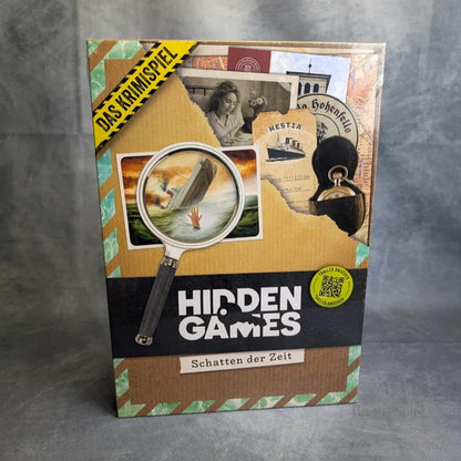 Eine Schachtel von Hidden Games Tatort: Schatten der Zeit von Hidden Games, mit einer Lupe über einer Landschaft, Dokumenten und der Aufschrift Das Krimispiel - perfekt für Ermittlungsspiel-Fans - in Deutsch mit einem gelben Banner.