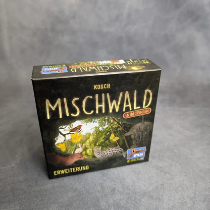 Eine Schachtel Mischwald - Entdeckungen von Brett&Spiel mit einem Cover, das Waldtiere, Pflanzen und Bäume vor einem schlichten grauen Hintergrund zeigt.