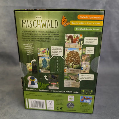 Die Rückseite der Asmodee-Kartenspielbox "Mischwald" zeigt illustrierte Karten mit Waldtieren, Pflanzen und einem Schmetterling sowie einen deutschen Text, der die einfachen Regeln und das naturbezogene Artwork in einem lebendigen Ökosystem beschreibt.