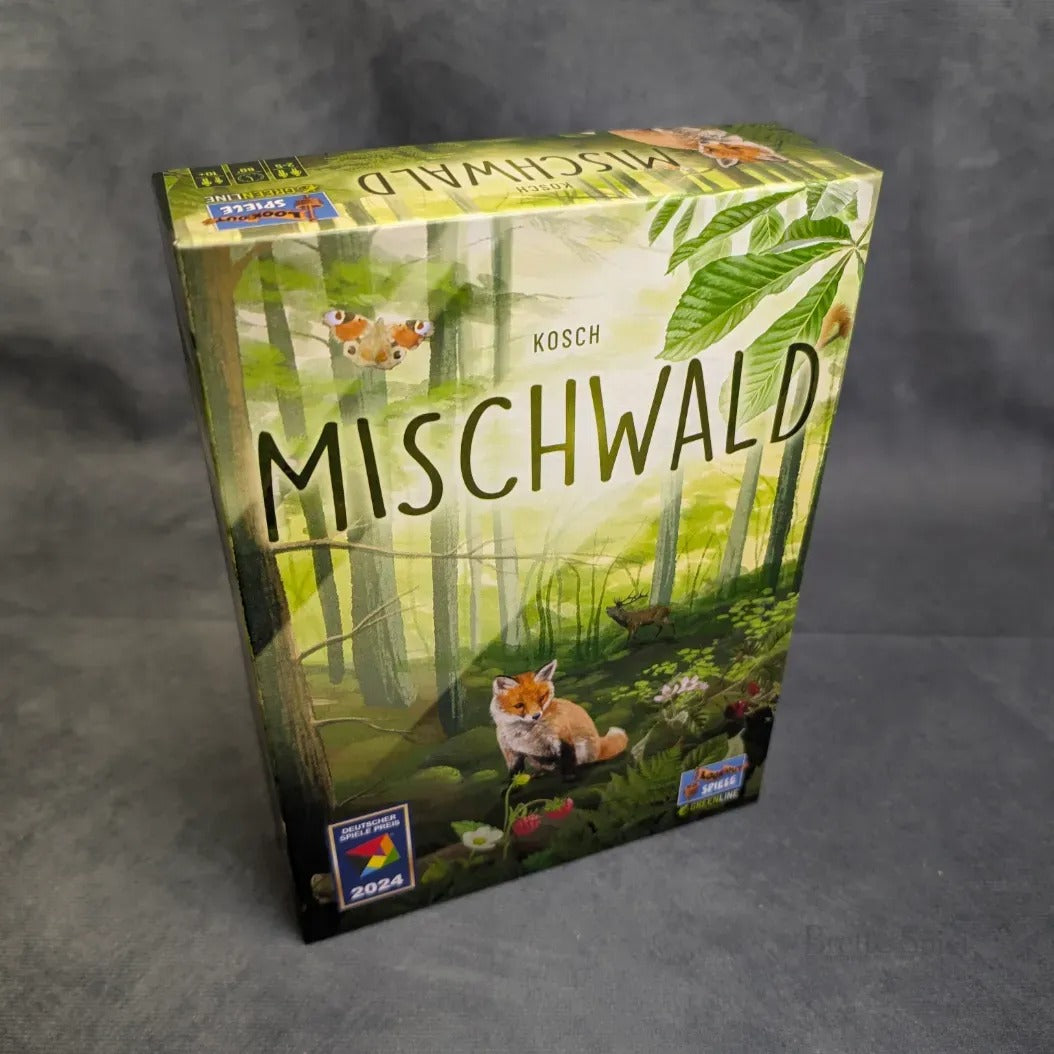 Eine Schachtel mit Mischwald von Asmodee, die auf dem Cover einen Fuchs, Schmetterlinge und einen üppigen Wald zeigt, mit mehreren Award-Logos, darunter 2024, die den Fokus auf das Ökosystem zeigen.