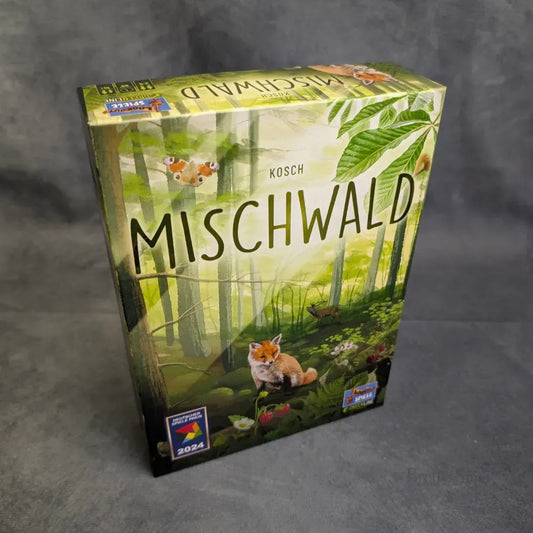Eine Schachtel mit Mischwald von Asmodee, die auf dem Cover einen Fuchs, Schmetterlinge und einen üppigen Wald zeigt, mit mehreren Award-Logos, darunter 2024, die den Fokus auf das Ökosystem zeigen.