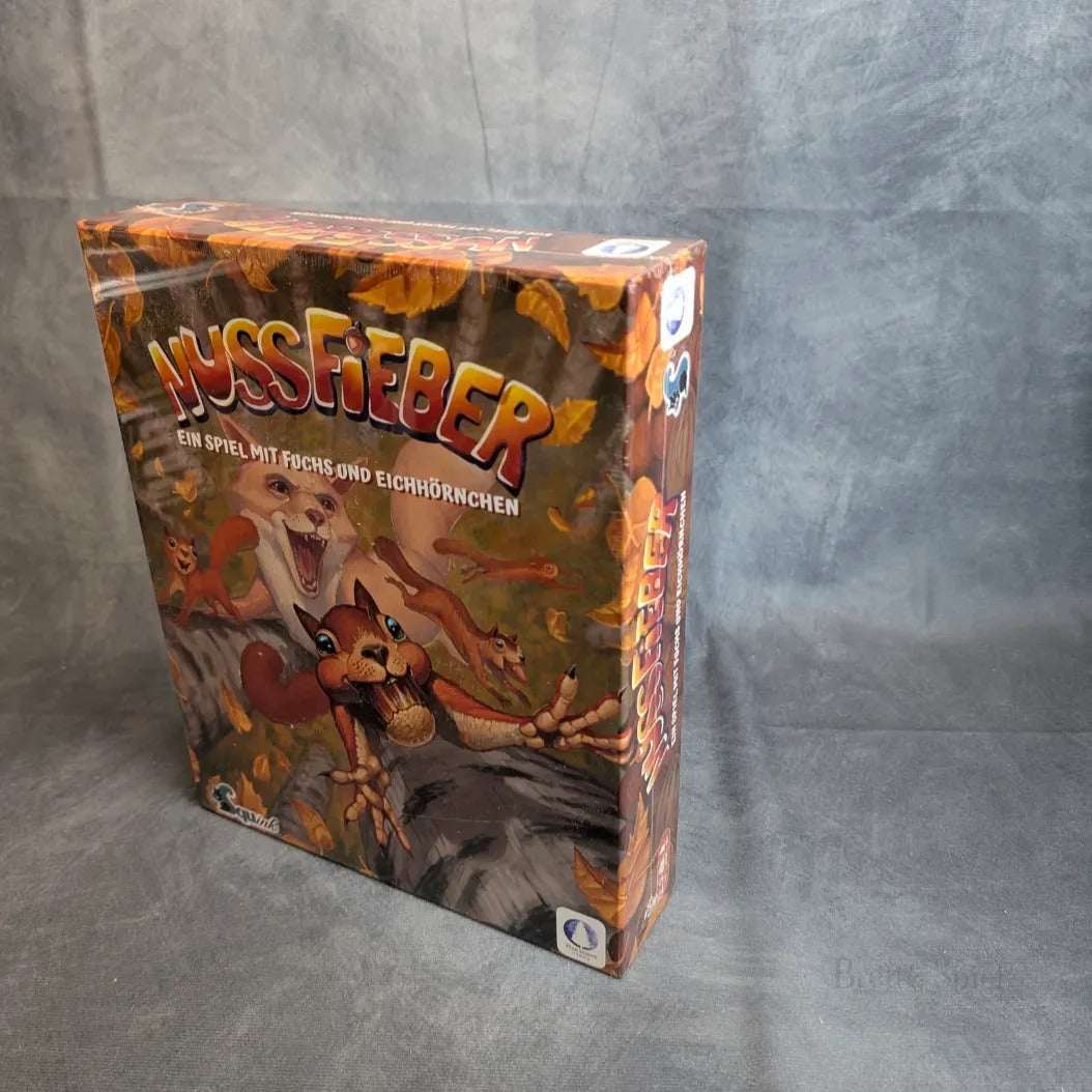 Die Spielschachtel Nussfieber der Squink GmbH ist eingeschweißt und zeigt auf dem Cover illustrierte Eichhörnchen und einen Fuchs, die nach herabfallenden Nüssen greifen, vor einem grau strukturierten Hintergrund.