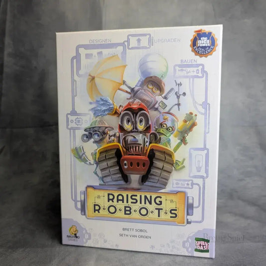 Das Cover des Brettspiels Raising Robots zeigt einladende Illustration von buunten Robotern mit vielen Gimmicks. Es deutet auf ein Familienfreundliches Spiel oder strategisches Aufbauspiel hin, bei dem es darum geht den besten Roboter zu bauen