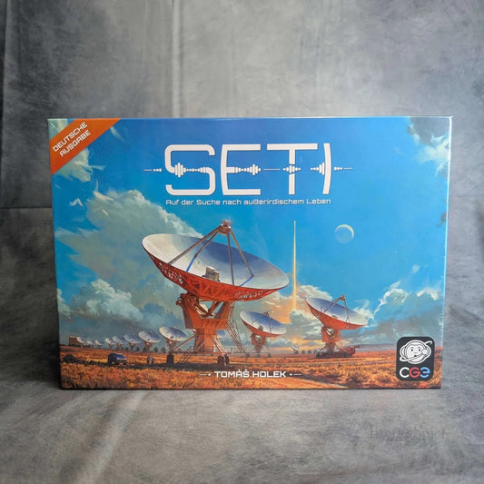 Die Schachtel des Brettspiels SETI: Auf der Suche nach auserirdischem Leben von HeidelBÄR Games zeigt Satellitenschüsseln in einer Wüste unter einem dramatischen Himmel, mit einem Raketenstart und dem deutschen Untertitel; das CGE-Logo befindet sich unten rechts.