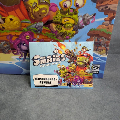 Eine Karte vor der Schachtel von Snails: Das Brettspiel + Abwurf Erweiterung von JoeKas World GmbH zeigt Cartoon-Schnecken in Helmen und Rüstungen und suggeriert ein taktisches Miniaturenspiel voller Action und Spaß.