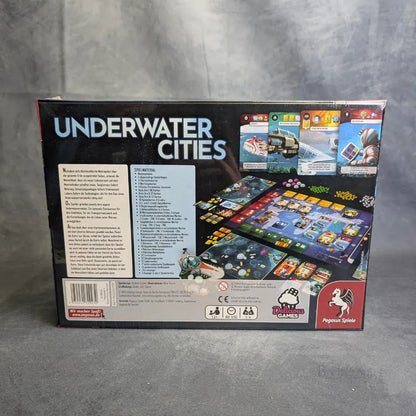 Die Rückseite der Schachtel von Underwater Cities von Pegasus Spiele zeigt farbenfrohe Karten, detaillierte Spielsteine, mehrsprachige Informationen und Markenlogos, die die Besonderheiten dieses innovativen Strategiespiels hervorheben.