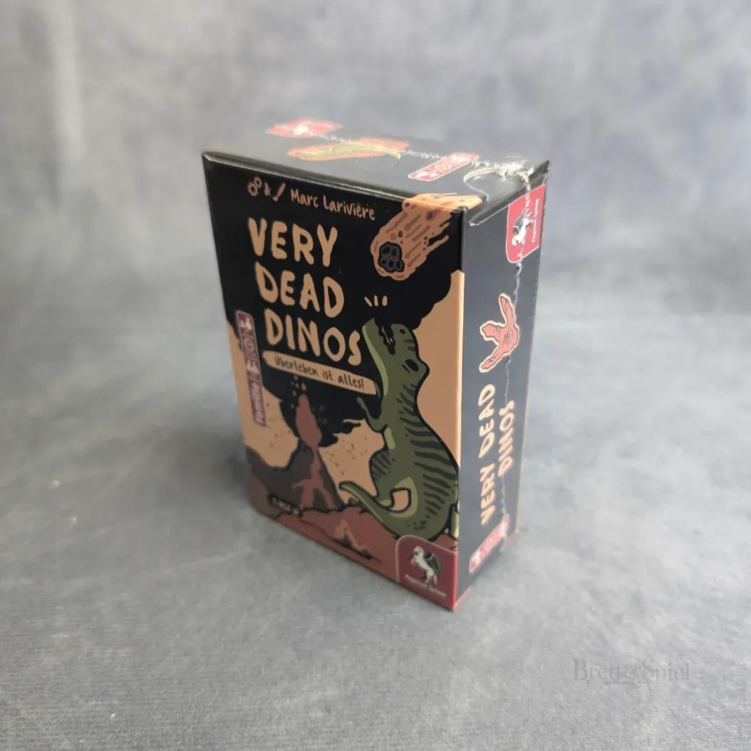 Very Dead Dinos - TRex von Pegasus Spiele ist ein kompaktes Kartenspiel mit Cartoon-Dinosauriern und einem Meteor, verpackt in einer schwarz-braunen Schachtel mit auffälligem Artwork und Schriftzug.