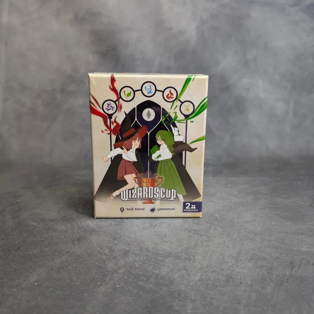 Wizards Cup von Boardgame Circus ist ein Kartenspiel in einer Schachtel, bei dem illustrierte Charaktere in strategischen Duellen Zaubersprüche wirken, mit magischen Symbolen über ihnen auf einem grauen Hintergrund.