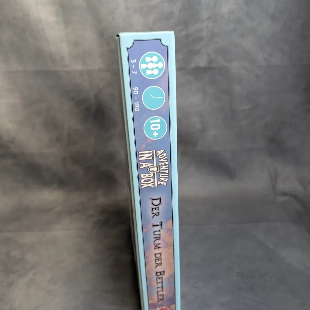 Der Buchrücken der Brettspielbox "Abenteuer in der Box: Sturmfels Akademie - Der Turm der Bettler" von Ulisses Spiele GmbH, ein Mini-RPG für 3-7 Spieler ab 10 Jahren, mit einer Spielzeit von 90-180 Minuten.