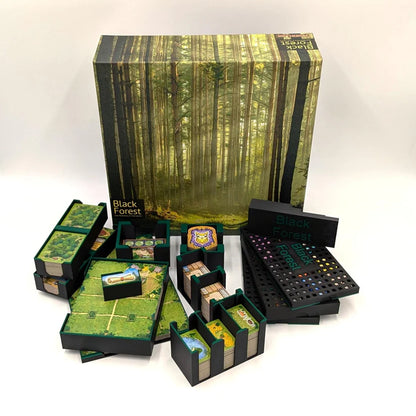 Das Brettspiel Black Forest wird mit seiner Schachtel gezeigt, die eine Waldszene zeigt. Spielfiguren, Karten, Spielsteine und Spielbretter werden mit dem 3D-Inset Black Forest Insert auf einer weißen Fläche angeordnet.