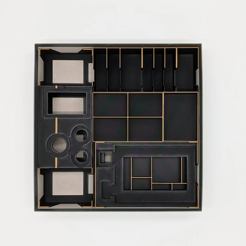 Eine Draufsicht auf einen leeren schwarzen Dune Imperium Einsatz von 3D-Inset, mit mehreren Fächern, um Ihre Spielschachtel organisiert und effizient in einer quadratischen Schachtel zu halten, gezeigt vor einem weißen Hintergrund.