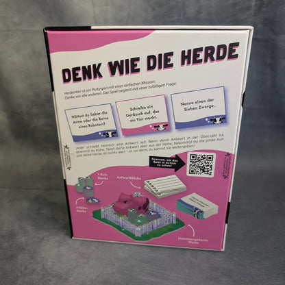 Das Bild zeigt die Rückseite einer Gesellschaftsspiel-Schachtel der Burst Spiele mit dem Titel „Herdentier“, auf der ein verspielter deutscher Text, farbenfrohe Illustrationen einer rosa Kuh und von Spielkarten, ein QR-Code sowie lebhafte lila-weiße Designelemente im Partyspiel-Stil zu sehen sind.